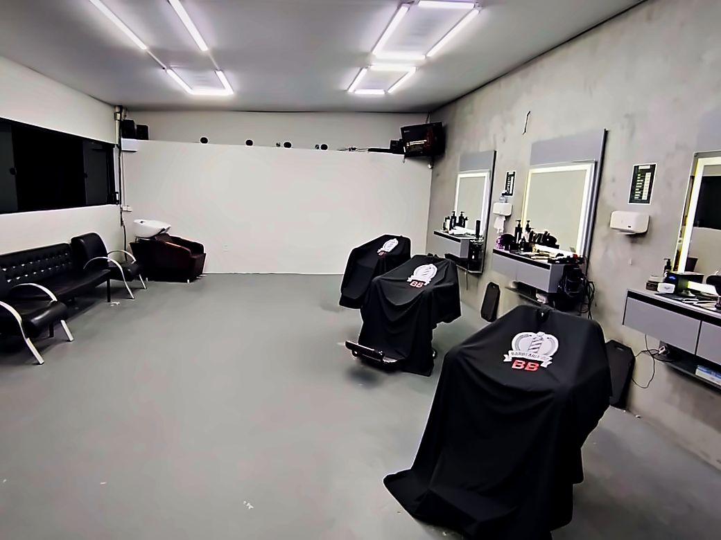 A cadeira da barbearia pronta, com a capa do brasão, esperando o próximo horário